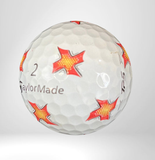 Golfball mit roten Sternmustern, TaylorMade Aufschrift, auf weißem Hintergrund