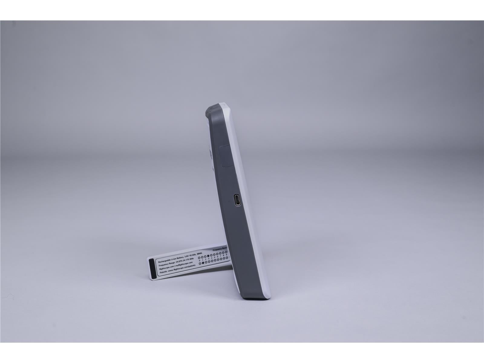 Golf-Launch-Monitor seitlich mit USB-Anschluss und ausklappbarem Standfuß auf grauem Hintergrund