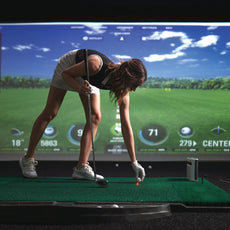Frau beim Golftraining auf Indoor Golf Simulator, Abschlagmatte, moderner Golfraum