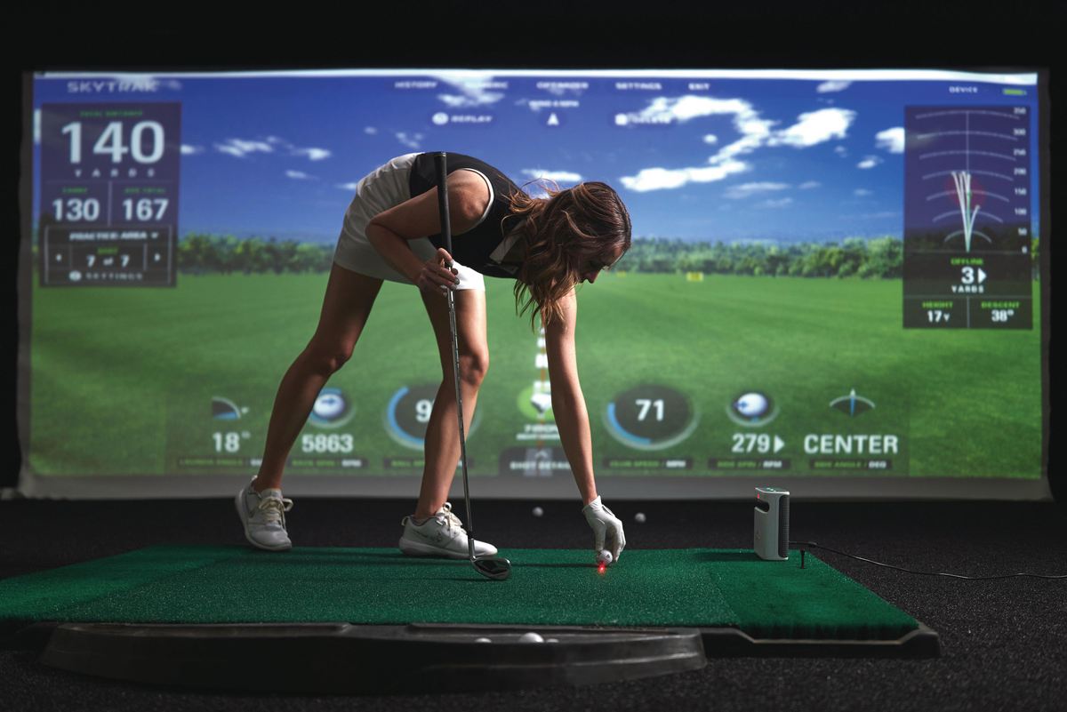 Frau beim Golftraining auf Indoor Golf Simulator, Abschlagmatte, moderner Golfraum