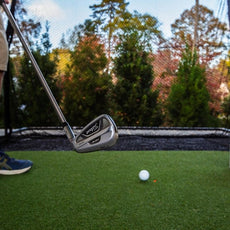 Golfspieler mit Eisen schlägt Golfball im Garten, Outdoor-Golfnetz und Golf Simulator