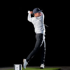 Golfspieler beim Abschlag auf Indoor-Golfmatte mit Golf Simulator und Launch Monitor