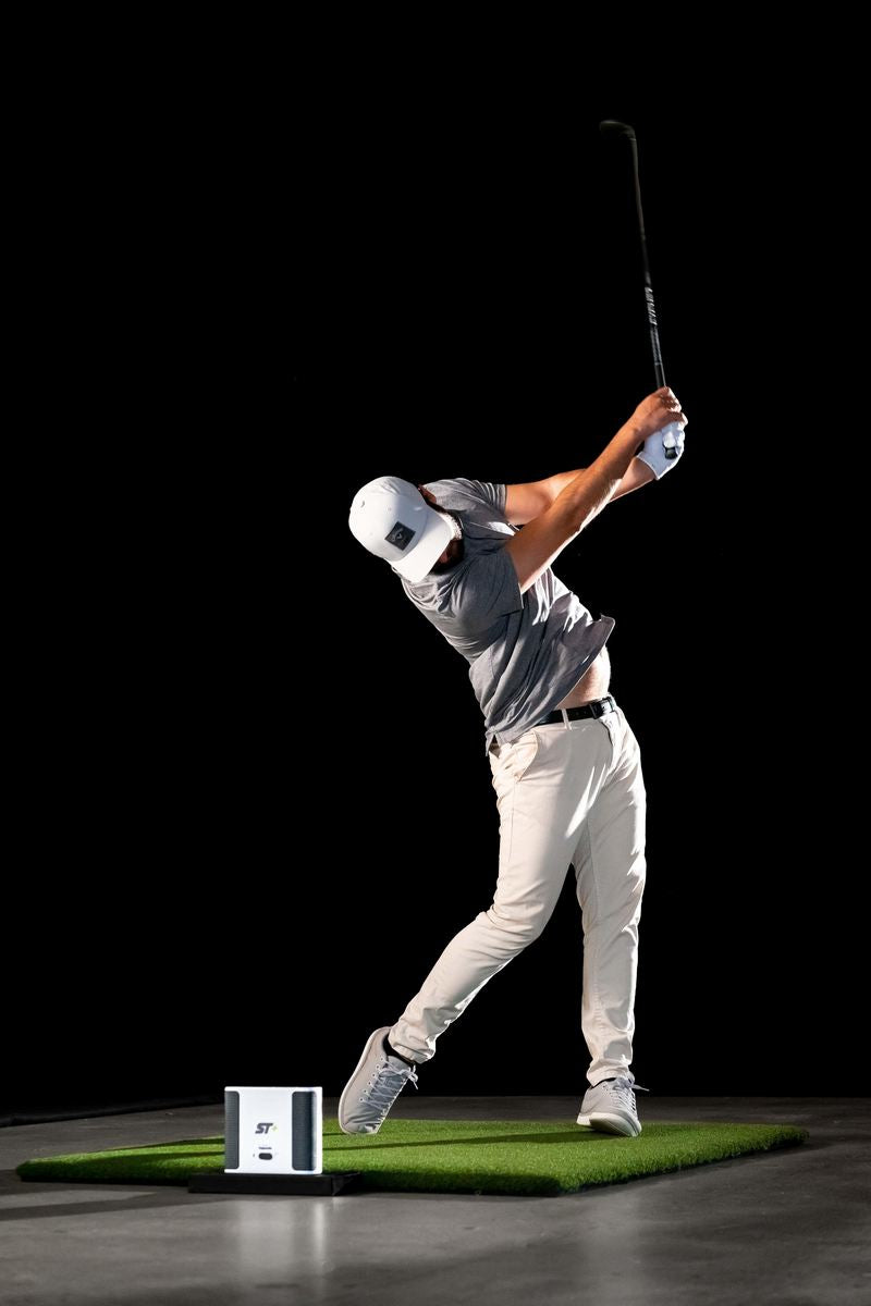 Golfer schlägt auf Indoor-Golfmatte mit Golf Simulator und Launch Monitor