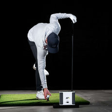 Golfer platziert Ball auf Abschlagmatte vor Golf Simulator und Launch Monitor, Indoor Golf Szene