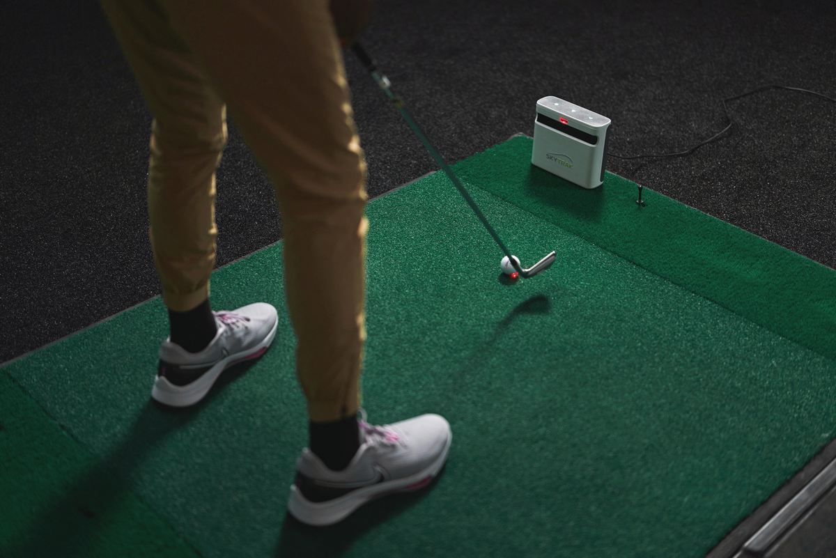 Golfer schlägt auf Indoor-Golfmatte mit Golfball und Launch Monitor, Golftraining Zubehör