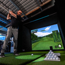 Golfer schlägt im modernen Indoor Golf Simulator mit realistischem Golfplatz-Display ab