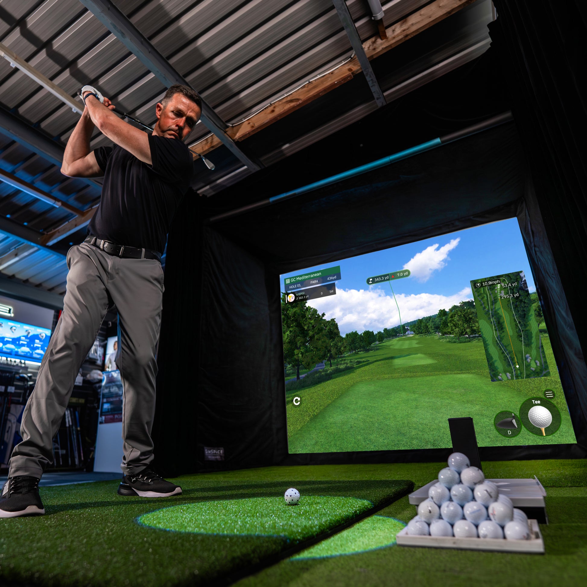 Golfer schlägt im modernen Indoor Golf Simulator mit realistischem Golfplatz-Display ab