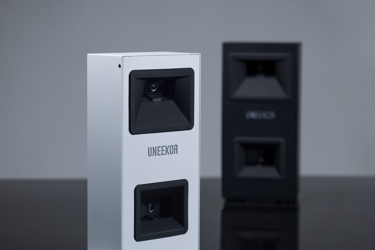 Zwei Uneekor Golf Launch Monitore, weiß und schwarz, für Indoor Golf Simulatoren auf Tisch.