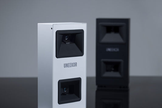 Zwei Uneekor Golf Launch Monitore, weiß und schwarz, für Indoor Golf Simulatoren auf Tisch.