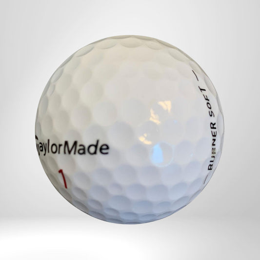 Weißer Golfball mit Aufschrift 'TaylorMade Burner Soft', Nahaufnahme auf hellem Hintergrund