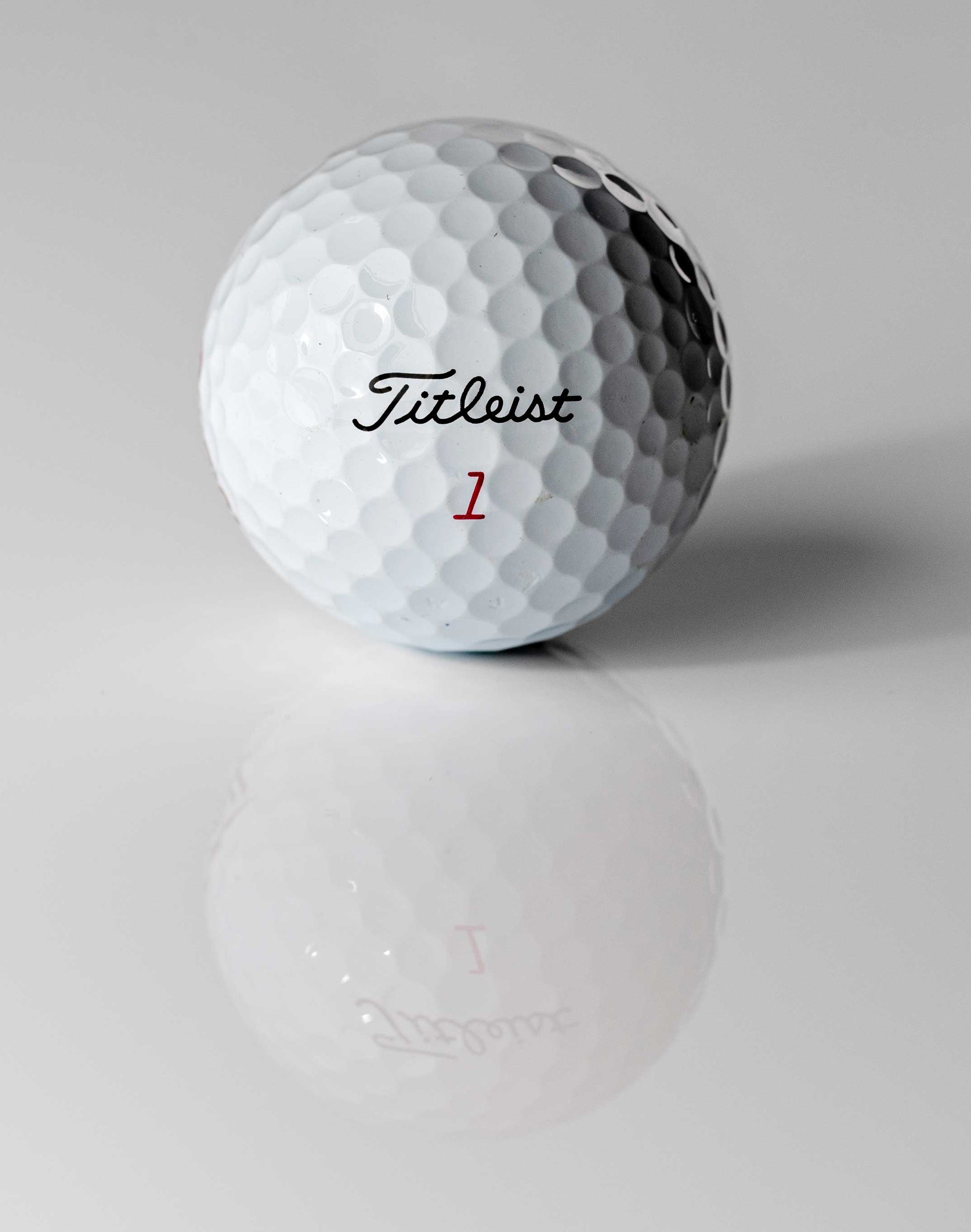 Nahaufnahme eines weißen Golfballs mit Titel-Logo und der Zahl 1, glänzende Oberfläche, Golf-Zubehör