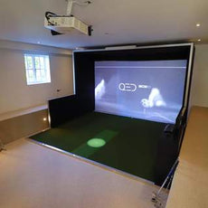 Moderner Indoor Golf Simulator mit großem Bildschirm und grünem Abschlagbereich